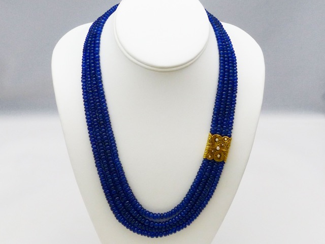 M-72C
Four strand necklace of royal blue sapphire rondelle beads, with Alex’s 18K yellow gold and diamond “Lilies” clasp. The sapphires total 585 carats, 11 diamonds in the clasp total 0.21 ct. 
Immediate delivery
$12,110.00
